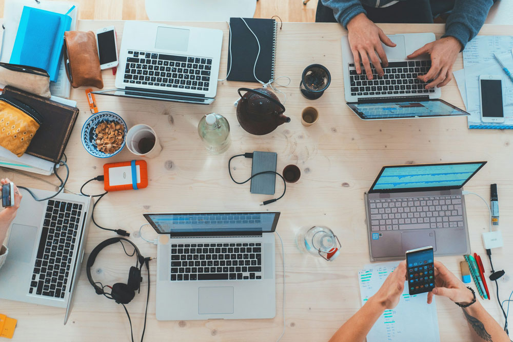 Birds eye point of view of multiple laptops at a table.